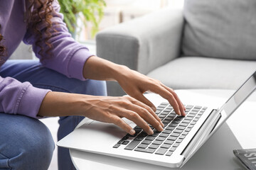 Young woman using laptop on table at home, closeup