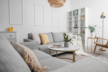 Interior of light living room with grey sofas, table and shelving unit