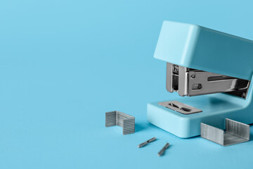 Stapler and staples on color background, closeup