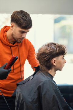 Vertical shot of a young Caucasian boy getting a fresh haircut