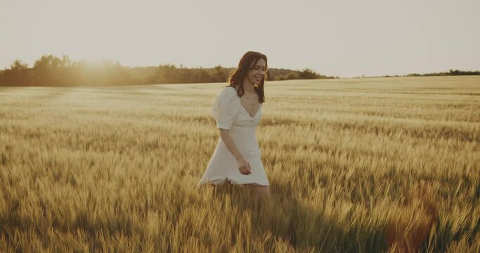 Beautiful Ukrainian young woman walking alone in yellow wheat meadow. Brunette girl in peace with summer nature. Relax freedom concept. Peaceful happy Ukraine. Floral landscape outdoors 4k slow motion