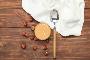 Bowl of tasty nut butter and hazelnuts on wooden background