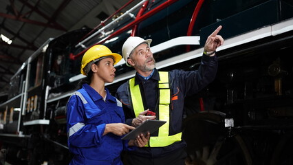 Group of apprentices with instructor at railway engineering facility. Teacher talking to...