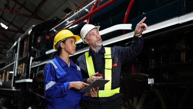 Group of apprentices with instructor at railway engineering facility. Teacher talking to apprentices at railway engineering facility