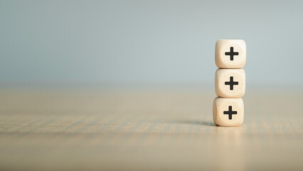 Plus sign in wooden cube block stacking. Addition and positive mindset thinking  such as profit,...