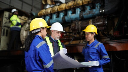 Fototapeta premium Engineers in discussion in machine maintenance in factory. Group of Industrial Engineers with Blueprint against trains and machinaries industry background.