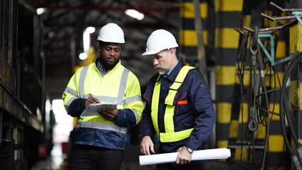 Portrait of engineer and apprentice in workshop of railway engineering facility