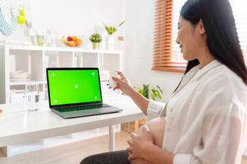 pregnant woman having online consultation with doctor on laptop at home. mockup green screen.