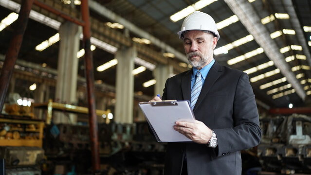 Factory manager or businessman owner in factory warehouse is talking on mobilephone. Business industry background.
