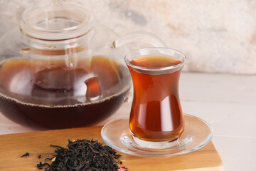 Glass cup of hot black tea on light table, closeup