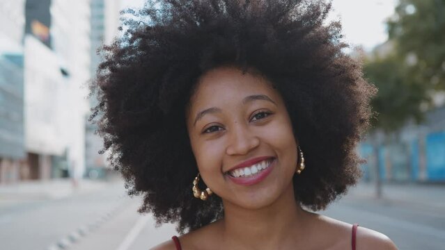 Cinematic video of a self confident young woman spending time in a modern city. Millennial girl with afro hairstyle lifestyle moments.