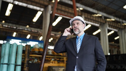 Factory manager or businessman in factory warehouse is talking on mobilephone. Factory indusrty Business.