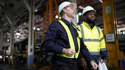 Portrait of engineer and apprentice in workshop of railway engineering facility