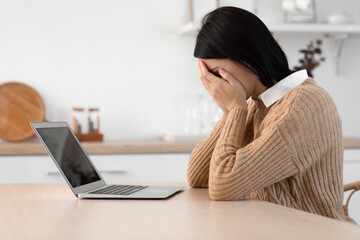Upset young woman video chatting with psychologist in kitchen