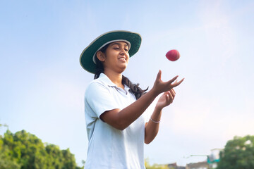 Girl wearing cricket uniform catching the ball on the field - Powered by Adobe