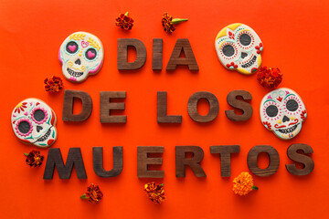 Text DIA DE LOS MUERTOS with cookies and flowers on red background