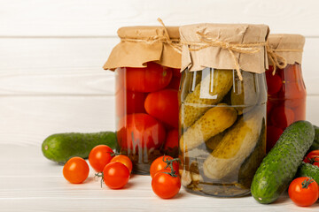 Jars with pickled vegetables. Pickled food.Jars of pickled vegetables: cucumbers and tomatoes on a...