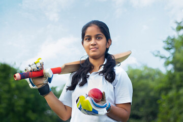 Portrait Of A Female Cricketer Holding A Cricket Bat And A Ball 