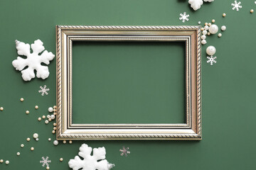 Composition with empty picture frame and Christmas decorations on green background