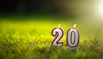 Burning candles in the form of numbers 20 on a green summer background. Congratulations on the...