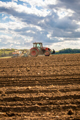 Agriculteur au volant de son tracteur labourant son champ de terre au printemps.