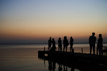 Fototapeta na wymiar Tourists waiting to take pictures at wooden dock in Albufera lake in Valencia at sunset