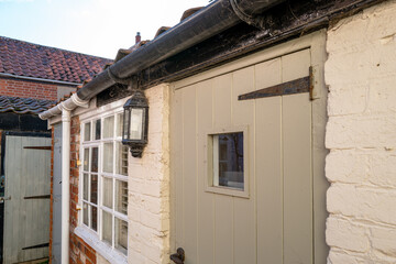 Shallow focus of a narrow back door seen at the entrance to an old holiday cottage. The small door leads to a kitchen.