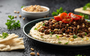 Hummus with spiced ground beef, olive oil, tomatoes and toasted pine nuts