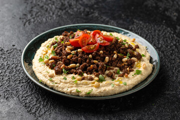 Hummus with spiced ground beef, olive oil, tomatoes and toasted pine nuts