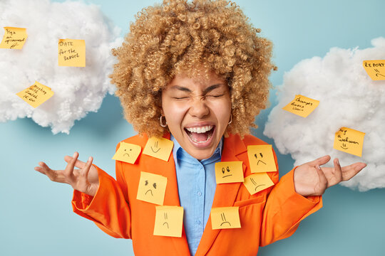 Emotional Female Worker Spreads Palms Has Much Wok To Do Dressed In Elegant Clothes With Sticky Notes On Jacket Makes List To Do Exclaims Loudly Isolated Over Blue Background Clouds Overhead