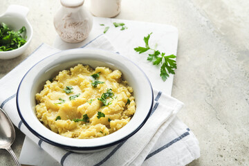 Mashed potatoes. Hot mashed potatoes with butter, fresh parsley herbs and pepper in bowl on slate, stone or concrete backgrounds. Delicious creamy mashed potatoes. Top view.