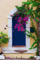 Fototapeta na wymiar Colorful blue door of traditional greek house with yellow walls at Asos village. Assos peninsula famous and extremely popular travel destination in Cephalonia, Greece, Europe.