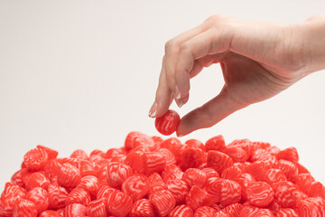 Woman hand takes a jelly candy on white background.