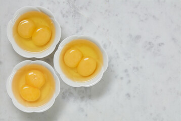 Double yolk eggs in a bowl on a white marble surface. Identical twins. Double eggs. 