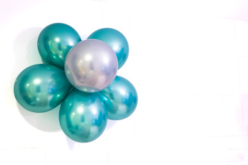 flower made of helium balloons in metallic colours green and silver, on a white background, copy space on the right, horizontal