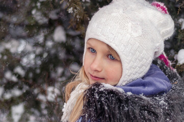 Winter day. A girl walks in a snowy park. Child on a walk in winter.