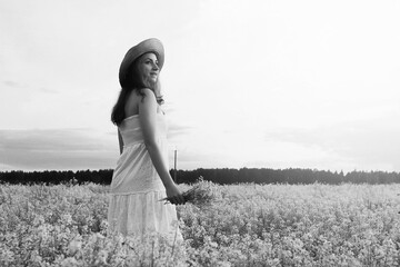 monochrome portrait of young girl in a hat standing in a huge field of flowers