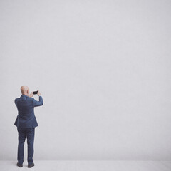 Businessman taking pictures of an empty wall