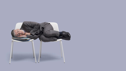 Exhausted businessman sleeping on chairs