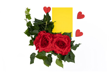Red roses on white background next to a piece of yellow paper and three red wooden hearts, space for text. 
