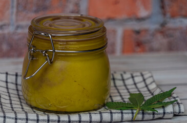 Yelllow marijuana butter on dark wooden table with dish towel