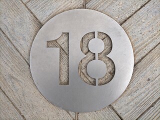 number eighteen, 18 in number, on a round metal plate on a wooden surface.