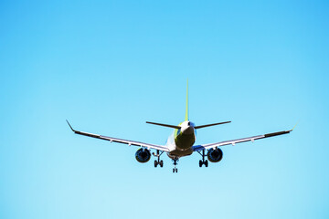 Fototapeta na wymiar An airplane flying in the lighht blue sky without any clouds