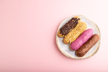 Set of eclair, traditional french dessert on ceramic plate on pink pastel background. top view, copy space.