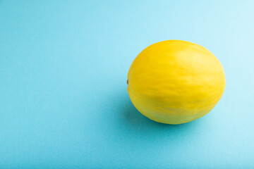 Ripe yellow melon on blue pastel background. Side view, copy space.