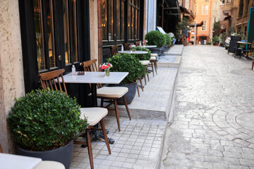 Tables and chairs standing outside near cafeteria on a summer day