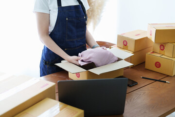 Fototapeta premium Starting small business entrepreneur of independent Asian woman smiling with cheerful success of online marketing package box items and SME delivery concept