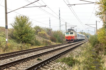 A passenger electric train runs in a foggy autumn morning. A railway line in the Czech Republic near the village of Hradcany. Train passenger transport.