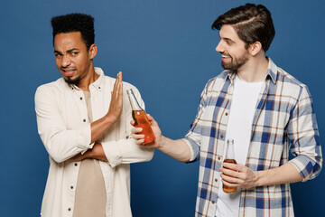 Side view young two friend teetotaler sad men in casual shirts together talk speak give bottle of...