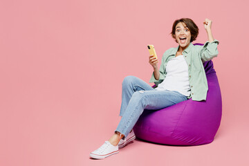 Full body young smiling happy overjoyed woman she wear green shirt white t-shirt sit in bag chair...